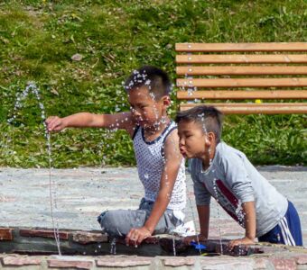 Grönländische Kinder beim Tropfen fangen am Brunnenplatz in Qaqortoq in Südgrönland